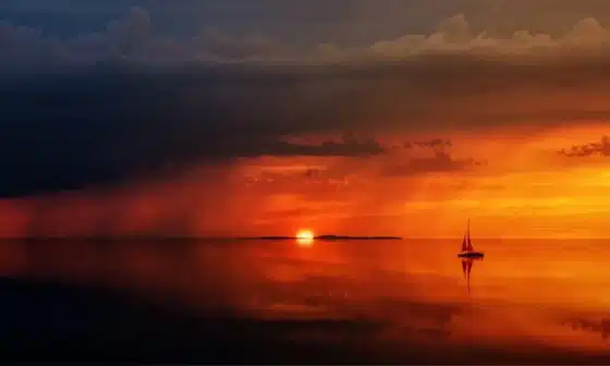 Image of an orange sun on the horizon with a small boat on still waters. the image subtly conveys the tone of the poem titled The First