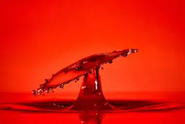 An abstract image of a red drop splash of water on a red background which captures the high passion and sensuality that is portrayed in in this poem title High Lust