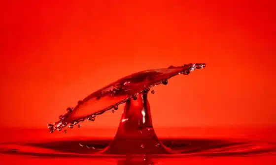 An abstract image of a red drop splash of water on a red background which captures the high passion and sensuality that is portrayed in in this poem title High Lust