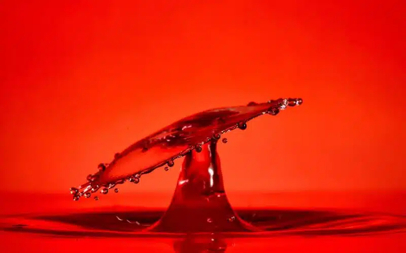 An abstract image of a red drop splash of water on a red background which captures the high passion and sensuality that is portrayed in in this poem title High Lust