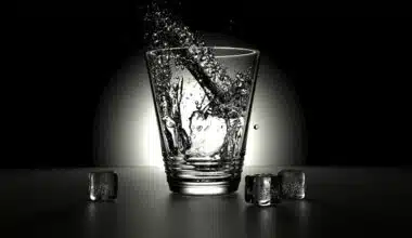 an abstract image of a shot glass with 3 ice cubes on a black background with a spot light on the glass. The glass is meant to accompany the poem title Lets Just conveying a sense of sensuality and exploration