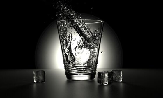 an abstract image of a shot glass with 3 ice cubes on a black background with a spot light on the glass. The glass is meant to accompany the poem title Lets Just conveying a sense of sensuality and exploration