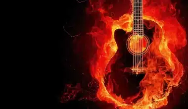 A burning guitar symbolizing passion for music, engulfed in flames against a black backdrop. "Musica è amore" - Music is love.