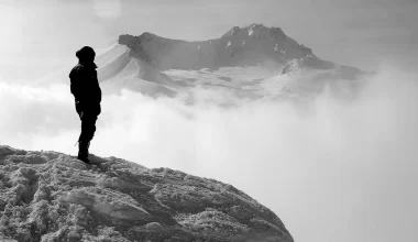 A man on a mountain peak, surrounded by clouds. Majestic view, inspiring heights. Nature's beauty captured in 'Pathways' poem.