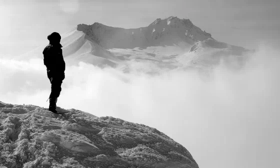 A man on a mountain peak, surrounded by clouds. Majestic view, inspiring heights. Nature's beauty captured in 'Pathways' poem.