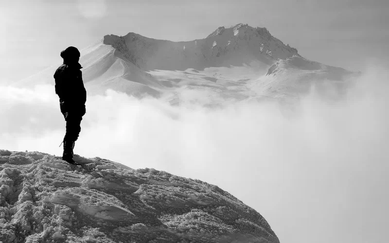 A man on a mountain peak, surrounded by clouds. Majestic view, inspiring heights. Nature's beauty captured in 'Pathways' poem.