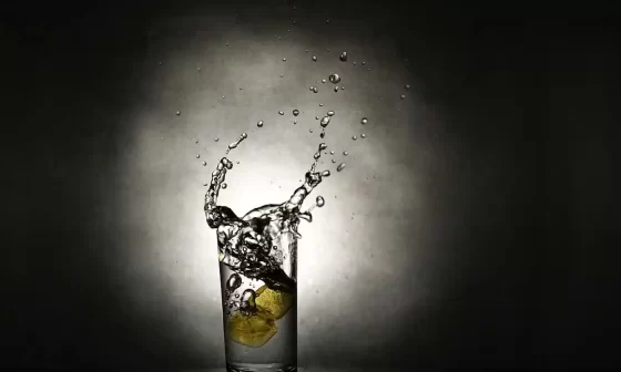 A refreshing glass of water with lemon slices, creating a splash. Poem: Into a winter.