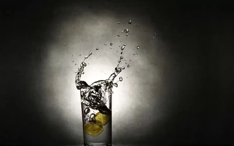 A refreshing glass of water with lemon slices, creating a splash. Poem: Into a winter.