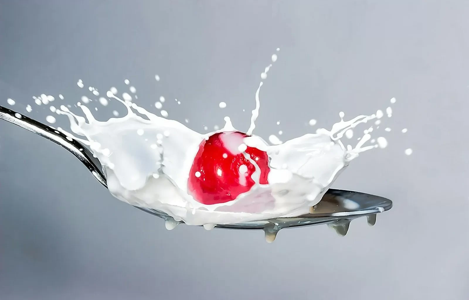 Milk splashing onto a spoon topped with a cherry.Entranced by their gaze, lost in a world of unparalleled beauty and emotion, words inadequate to convey the depth of feeling.