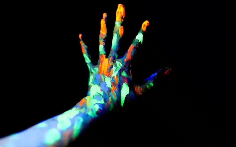 A hand covered in glow in the dark paint, creating a mesmerizing and luminous effect. A passionate scene where two lovers immerse in each other