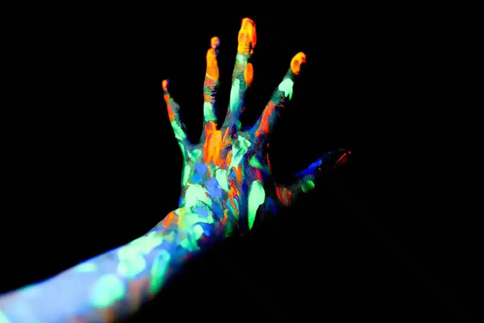 A hand covered in glow in the dark paint, creating a mesmerizing and luminous effect. A passionate scene where two lovers immerse in each other