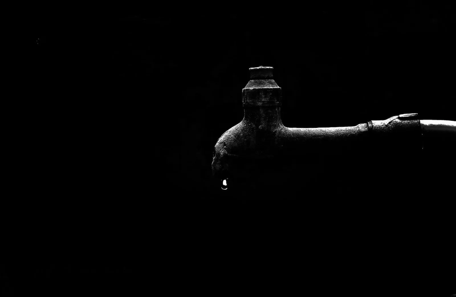 An evocative image of a hand holding a water faucet in black and white, symbolizing the battle between a thirst for love and a growing sense of disillusionment.