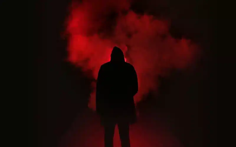 An individual in front of a red smoke cloud, exploring the haunting of my self, finding comfort in seeking understanding.