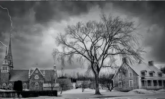 A serene black and white photo of a church surrounded by trees. A peaceful scene that inspires reflection and faith.