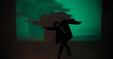 A man gracefully dances in front of a green screen, embodying the essence of life's dualities - darkness and light, joy and sorrow.