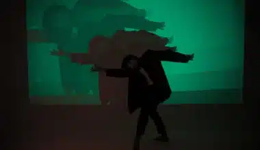 A man gracefully dances in front of a green screen, embodying the essence of life's dualities - darkness and light, joy and sorrow.