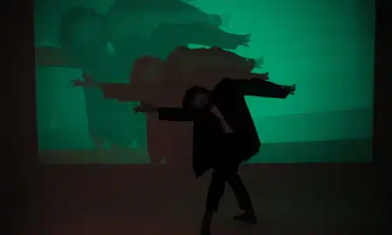 A man gracefully dances in front of a green screen, embodying the essence of life's dualities - darkness and light, joy and sorrow.