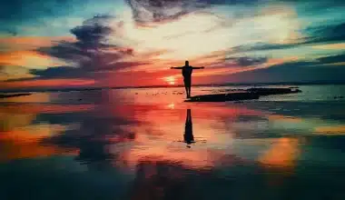 Journey through the Mist: Labyrinth of Self-Epic Poem-A person standing on the beach at sunset, seeking meaning in introspection, confronting masks, embracing vulnerability